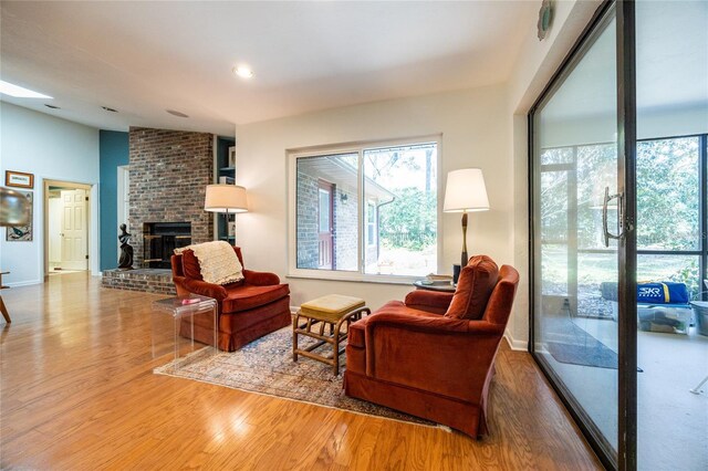 living room featuring wood finished floors, baseboards, lofted ceiling, a fireplace, and recessed lighting