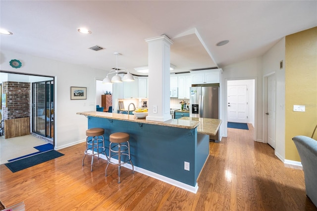 kitchen with a breakfast bar, appliances with stainless steel finishes, visible vents, and white cabinetry