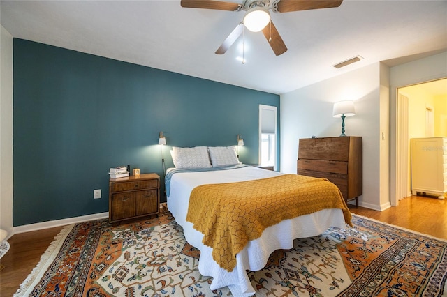 bedroom featuring visible vents, baseboards, wood finished floors, and a ceiling fan