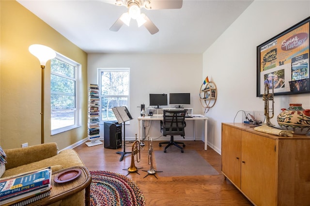 office space featuring a ceiling fan, baseboards, and wood finished floors