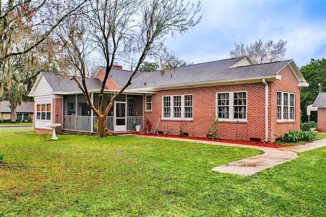 back of property with brick siding, a shingled roof, a sunroom, a yard, and a chimney