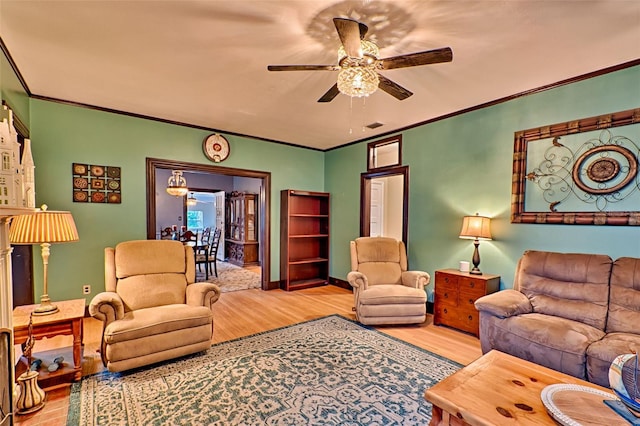 living room with light wood-style flooring, visible vents, ornamental molding, and a ceiling fan