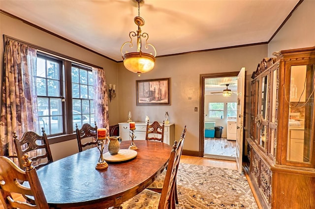 dining space with light wood finished floors, ornamental molding, and baseboards