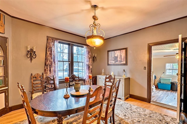 dining room featuring light wood-style flooring, baseboards, and crown molding