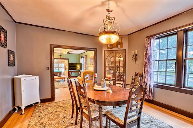 dining area featuring ornamental molding, baseboards, and light wood finished floors