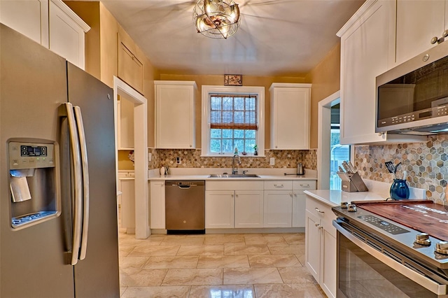 kitchen featuring appliances with stainless steel finishes, white cabinets, light countertops, and plenty of natural light