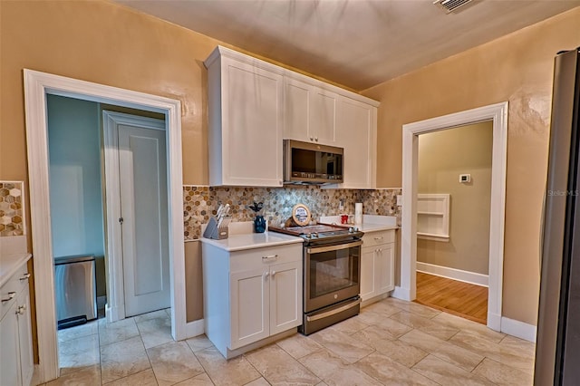 kitchen featuring stainless steel appliances, white cabinets, light countertops, and decorative backsplash