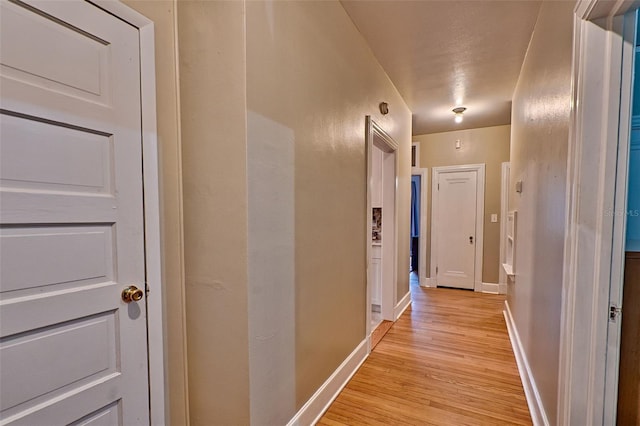 hallway featuring light wood-style flooring and baseboards