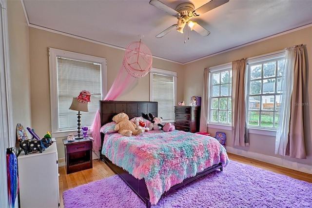 bedroom featuring light wood-style floors, ornamental molding, baseboards, and ceiling fan