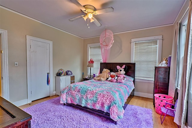 bedroom with light wood-style floors, crown molding, baseboards, and a ceiling fan