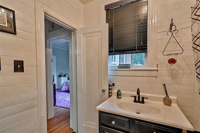 bathroom featuring wood walls, wood finished floors, and vanity