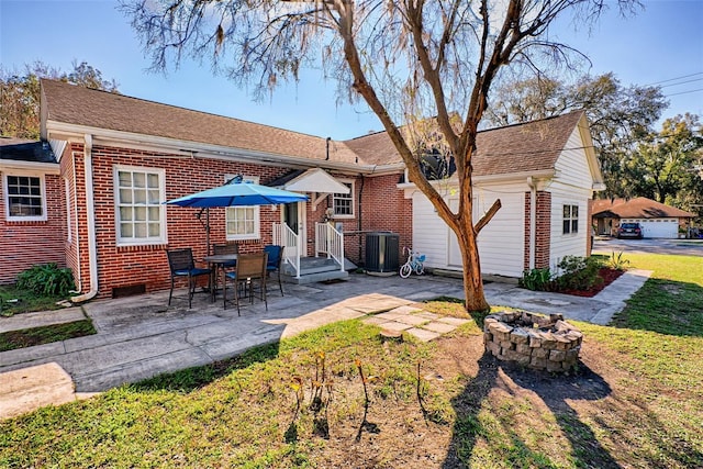 back of property with central air condition unit, a patio area, a fire pit, and brick siding