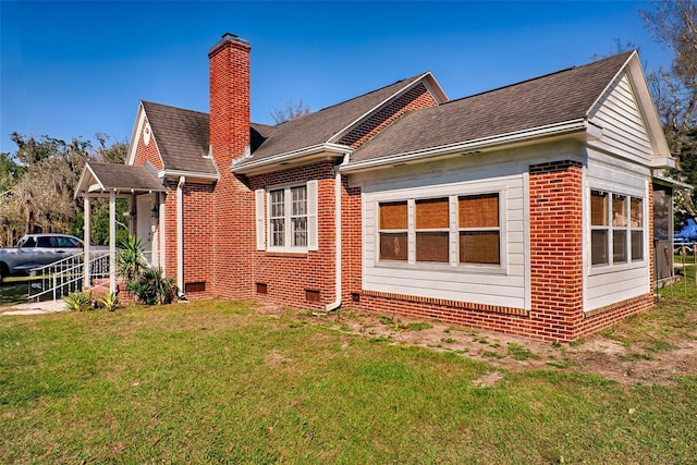 back of property with brick siding, a yard, a chimney, a shingled roof, and crawl space