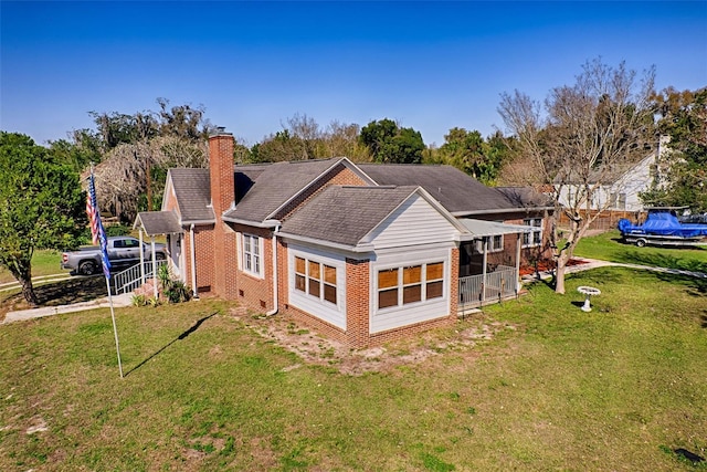 rear view of property featuring a yard, a chimney, and brick siding