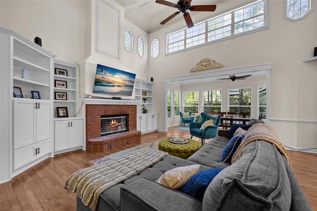 living room featuring a fireplace, light wood-style floors, baseboards, and a ceiling fan