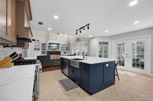 kitchen featuring tasteful backsplash, french doors, a fireplace, stainless steel appliances, and a sink