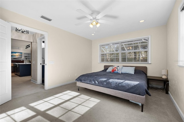 bedroom featuring visible vents, light colored carpet, baseboards, and ceiling fan