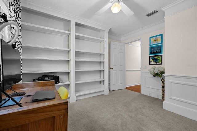 office space featuring visible vents, ornamental molding, a ceiling fan, wainscoting, and carpet flooring