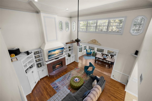 living area with a fireplace, ceiling fan, and wood finished floors