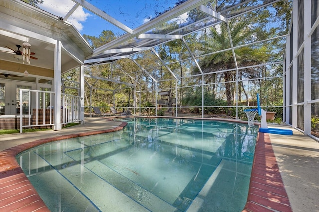 pool with glass enclosure, a patio area, and ceiling fan