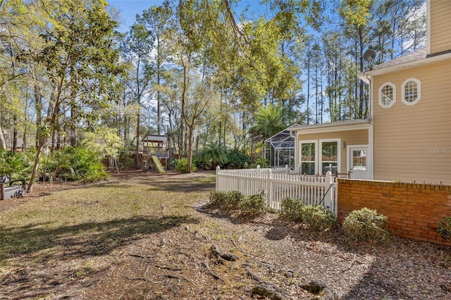 view of yard with a lanai, a playground, and fence