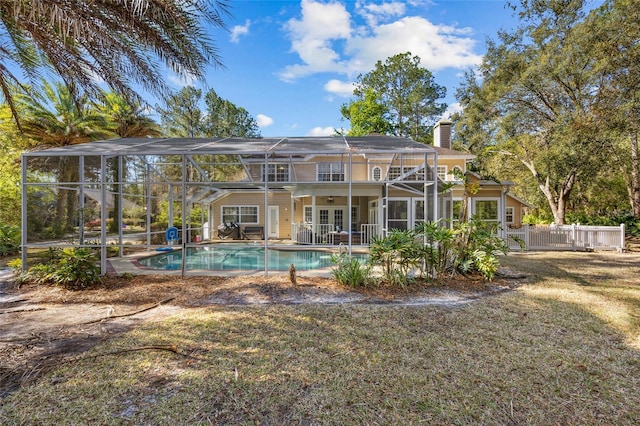 rear view of house with a lanai, french doors, an outdoor pool, and a chimney