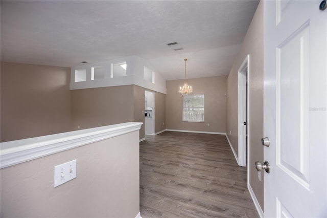 entryway featuring lofted ceiling, baseboards, a chandelier, and wood finished floors