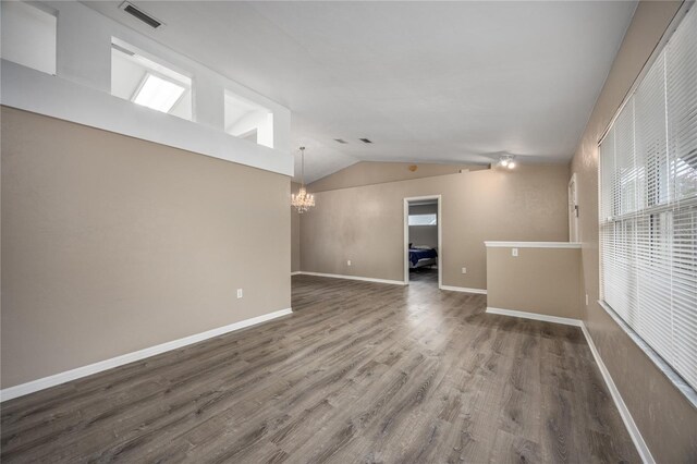 spare room with dark wood-style floors, visible vents, an inviting chandelier, vaulted ceiling, and baseboards