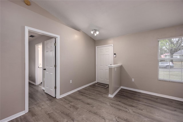 interior space with lofted ceiling, visible vents, baseboards, and wood finished floors