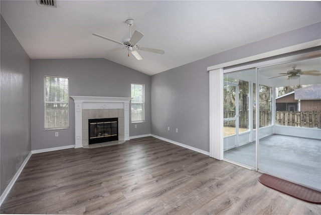 unfurnished living room featuring lofted ceiling, ceiling fan, a tiled fireplace, and wood finished floors