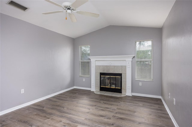 unfurnished living room with plenty of natural light, visible vents, dark wood finished floors, and a tiled fireplace