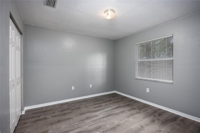 unfurnished room featuring baseboards, visible vents, and wood finished floors