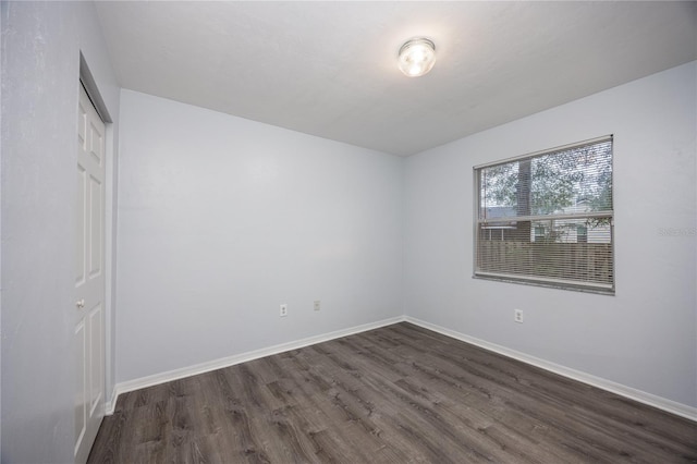 unfurnished bedroom featuring dark wood-type flooring, a closet, and baseboards