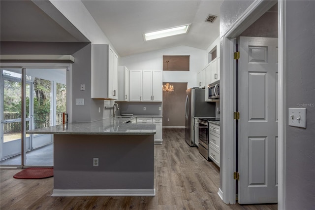 kitchen with visible vents, appliances with stainless steel finishes, a peninsula, white cabinetry, and a sink