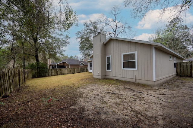 back of property with a chimney and a fenced backyard