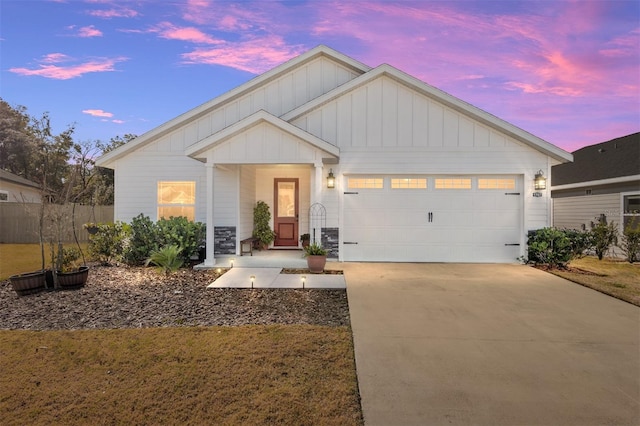 view of front of house with a garage, driveway, board and batten siding, and fence