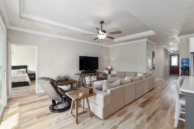 living area featuring light wood-type flooring, a raised ceiling, and crown molding