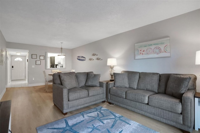 living room with a textured ceiling, baseboards, and wood finished floors