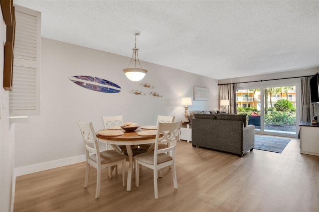 dining area with light wood-style floors, baseboards, and a textured ceiling