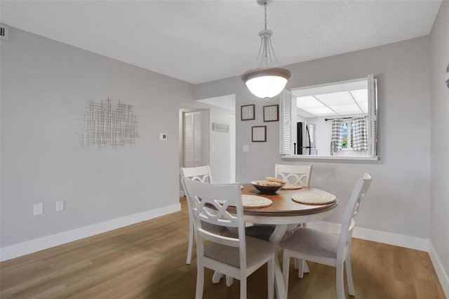 dining area featuring visible vents, baseboards, and wood finished floors