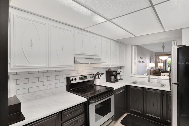 kitchen with backsplash, appliances with stainless steel finishes, white cabinetry, a sink, and under cabinet range hood