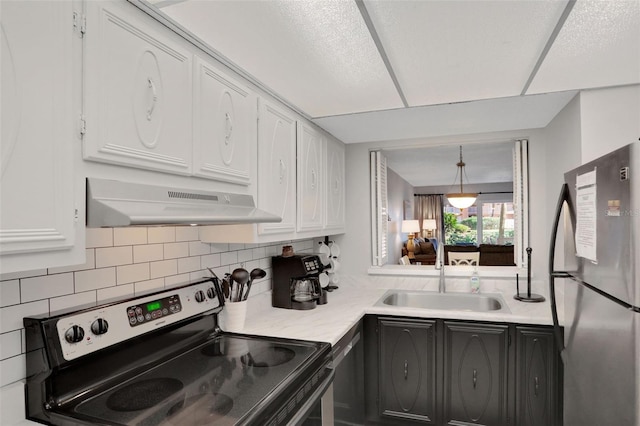 kitchen featuring white cabinets, stainless steel appliances, light countertops, under cabinet range hood, and a sink