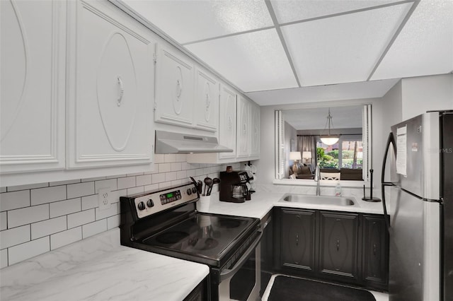 kitchen featuring white cabinets, appliances with stainless steel finishes, light countertops, under cabinet range hood, and a sink