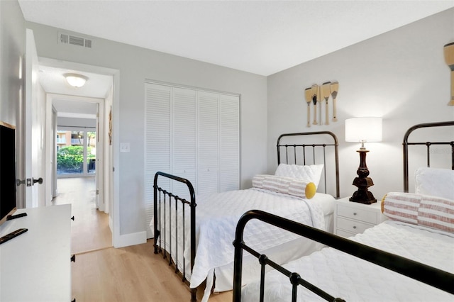 bedroom with a closet, light wood-type flooring, visible vents, and baseboards