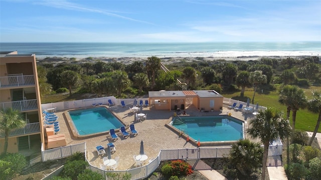 pool with a patio, a water view, and fence