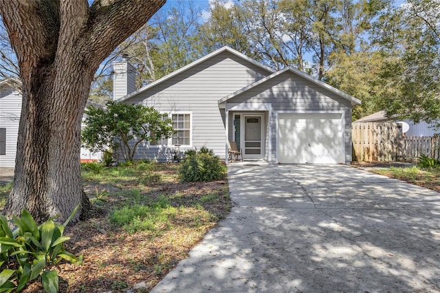 view of front of home featuring a garage, driveway, a chimney, and fence