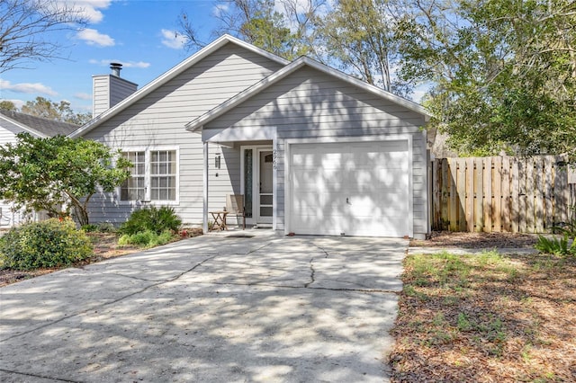 view of front of property with concrete driveway, fence, a chimney, and an attached garage