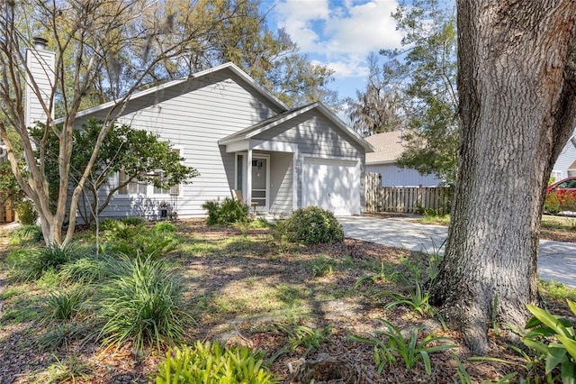 view of front of property featuring a garage, concrete driveway, and fence