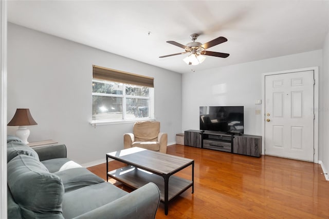 living area featuring wood finished floors, a ceiling fan, and baseboards