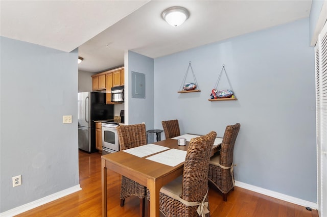 dining area featuring electric panel, baseboards, and wood finished floors